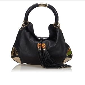 Gucci Indy has a leather body with gold-tone metal, bamboo and tassel details